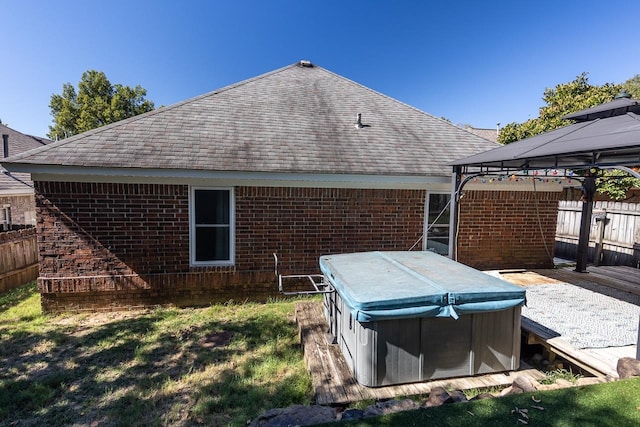 back of house featuring a hot tub and a gazebo