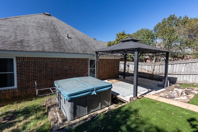 deck featuring a gazebo, a hot tub, and a lawn