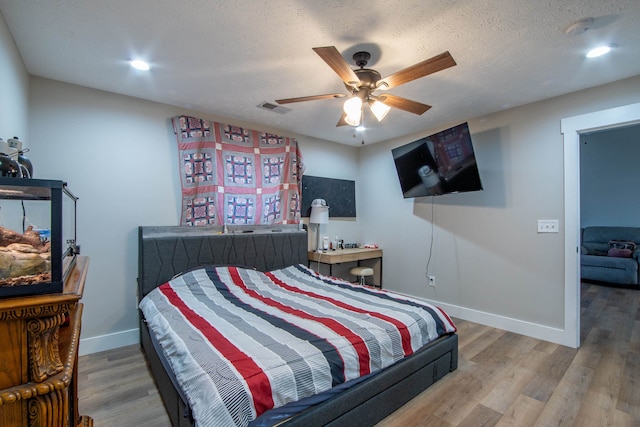 bedroom with ceiling fan, a textured ceiling, and hardwood / wood-style floors