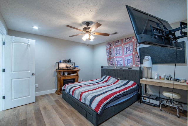 bedroom with hardwood / wood-style floors, a textured ceiling, and ceiling fan