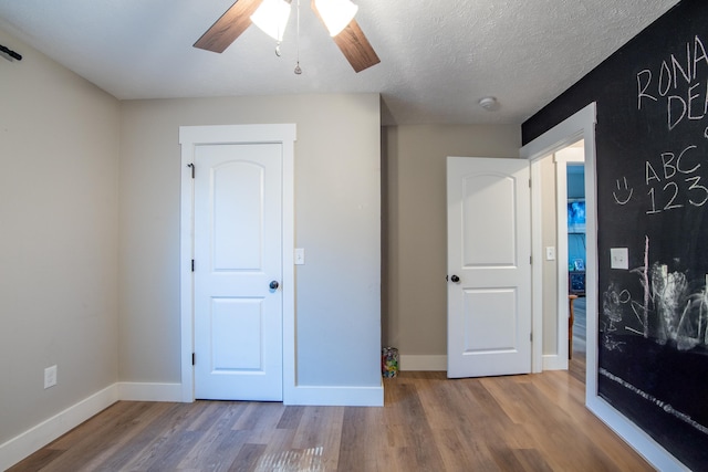 unfurnished bedroom featuring hardwood / wood-style floors, a textured ceiling, and ceiling fan