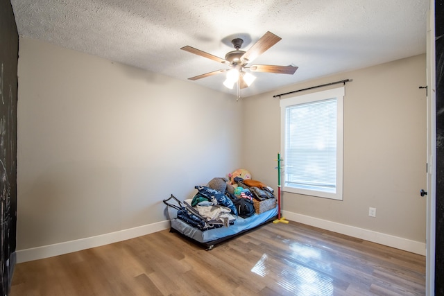 unfurnished bedroom featuring a textured ceiling, wood-type flooring, and ceiling fan