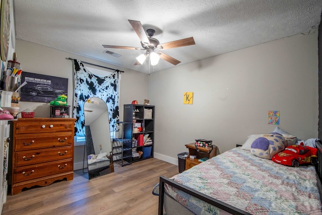 bedroom with a textured ceiling, hardwood / wood-style flooring, and ceiling fan