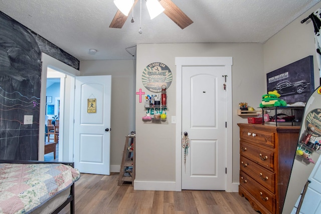 bedroom with ceiling fan, hardwood / wood-style flooring, and a textured ceiling