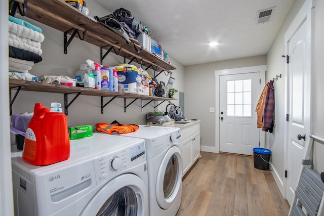 washroom with light hardwood / wood-style flooring, cabinets, and separate washer and dryer