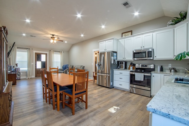 kitchen featuring lofted ceiling, white cabinets, and stainless steel appliances