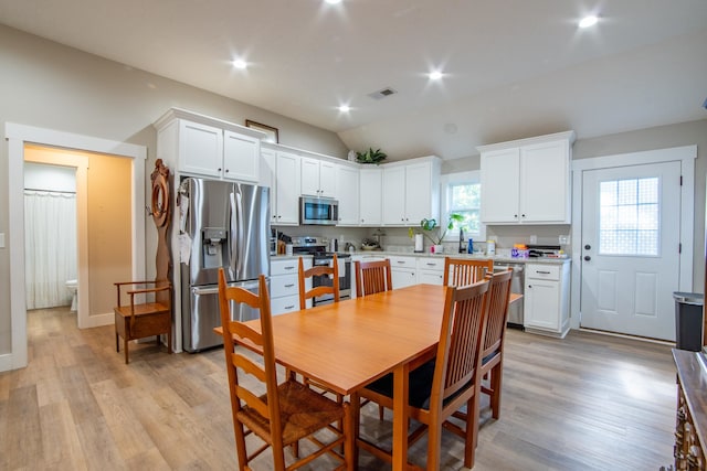 dining space with light hardwood / wood-style flooring and lofted ceiling