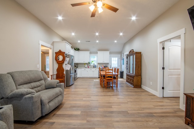 living room with light hardwood / wood-style flooring, ceiling fan, sink, and vaulted ceiling