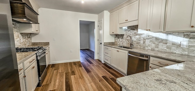 kitchen with light stone countertops, appliances with stainless steel finishes, sink, custom exhaust hood, and dark wood-type flooring