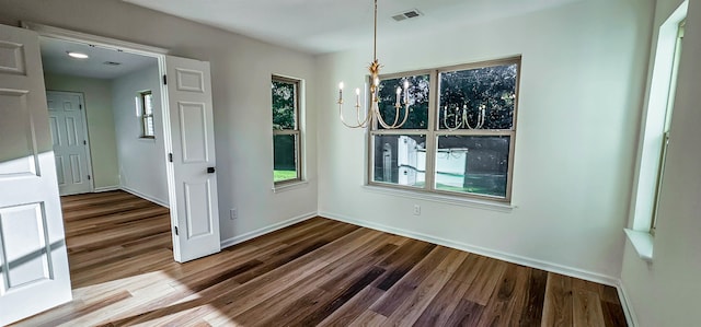 unfurnished dining area featuring an inviting chandelier and wood-type flooring