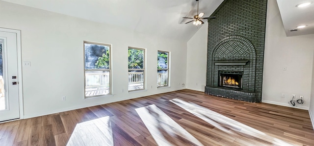 unfurnished living room featuring hardwood / wood-style flooring, high vaulted ceiling, a fireplace, and ceiling fan