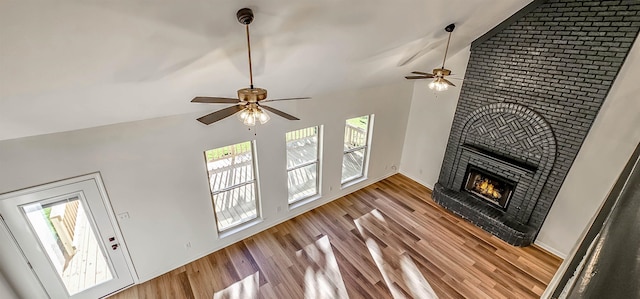 living room featuring light hardwood / wood-style floors, high vaulted ceiling, a fireplace, and ceiling fan