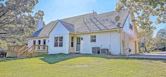 rear view of house featuring a wooden deck, a yard, and a garage