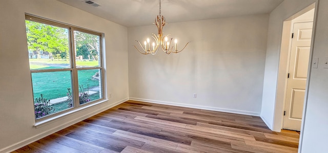 unfurnished dining area featuring a notable chandelier and hardwood / wood-style floors