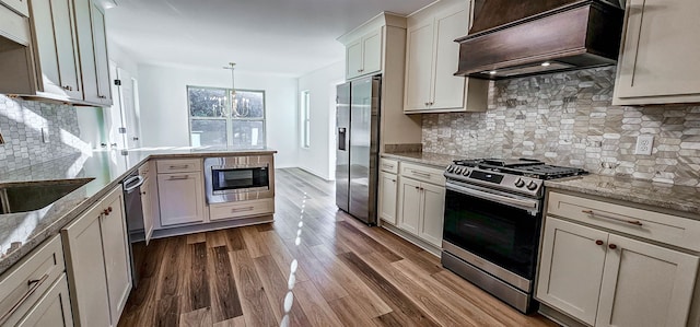 kitchen featuring kitchen peninsula, premium range hood, dark wood-type flooring, pendant lighting, and stainless steel appliances