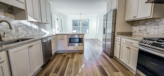 kitchen with light stone countertops, appliances with stainless steel finishes, decorative light fixtures, and dark hardwood / wood-style floors