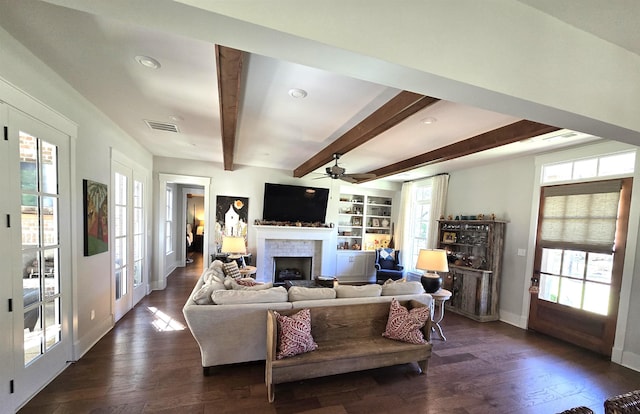 living room featuring ceiling fan, built in features, beamed ceiling, and dark hardwood / wood-style flooring