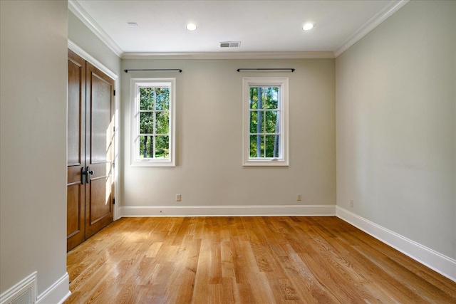 spare room with crown molding, light hardwood / wood-style flooring, and plenty of natural light