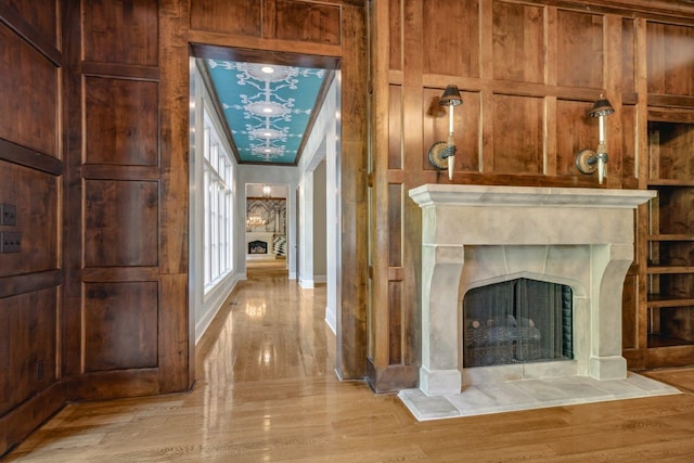 hallway featuring light hardwood / wood-style floors, ornamental molding, and wooden walls