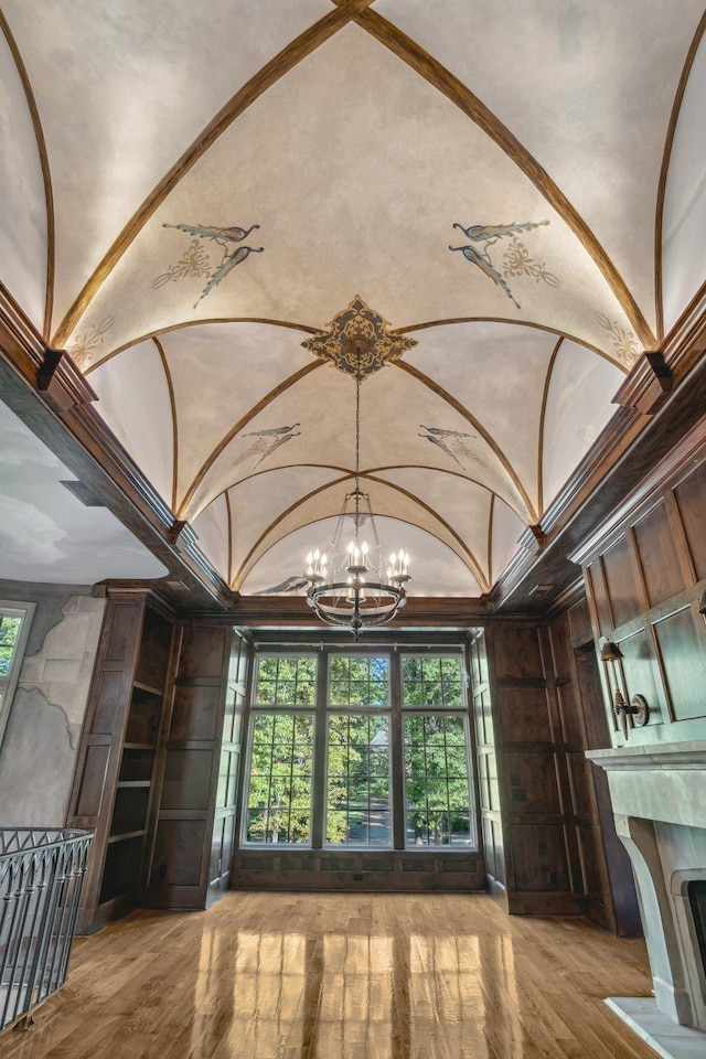 interior space featuring lofted ceiling, crown molding, hardwood / wood-style flooring, and an inviting chandelier