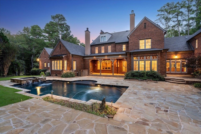 back house at dusk with a patio, pool water feature, french doors, and a swimming pool with hot tub