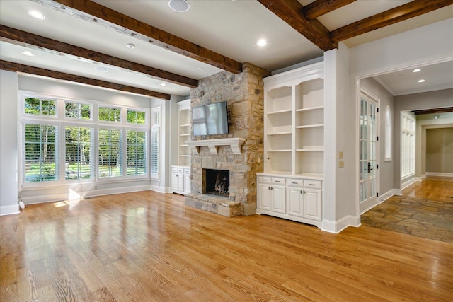 unfurnished living room with a fireplace, ornamental molding, beamed ceiling, and light wood-type flooring