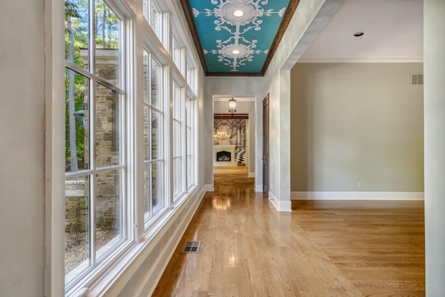 corridor featuring ornamental molding, a wealth of natural light, and light wood-type flooring