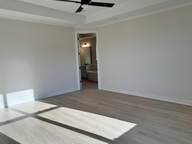 unfurnished room featuring ceiling fan, dark wood-type flooring, and a tray ceiling