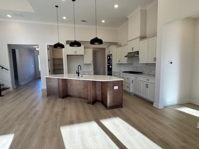 kitchen with extractor fan, a spacious island, black appliances, decorative backsplash, and white cabinets