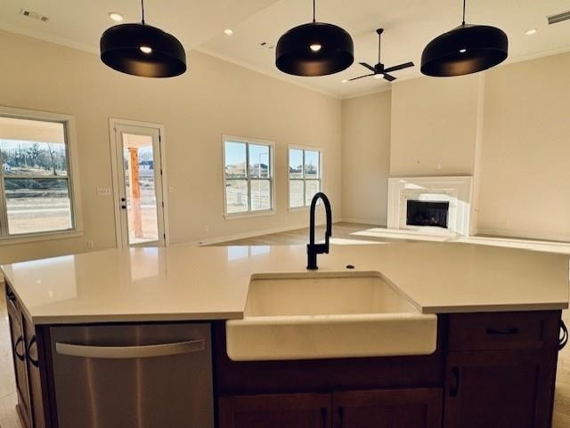 kitchen featuring ornamental molding, stainless steel dishwasher, a center island with sink, and sink