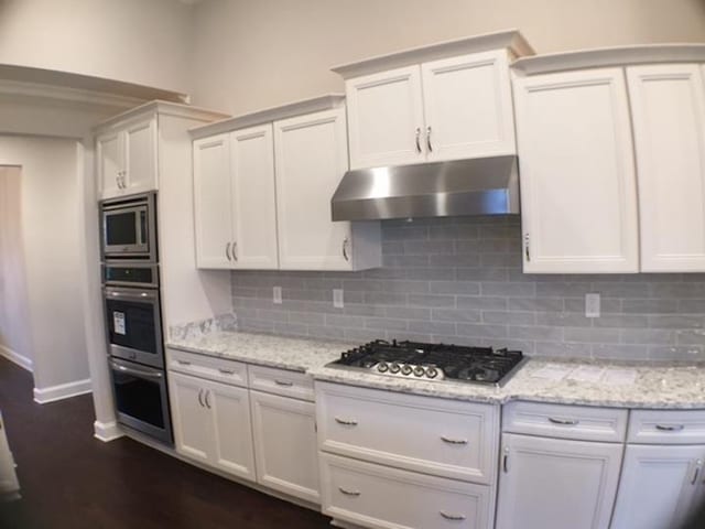 kitchen with white cabinetry, stainless steel appliances, and light stone counters