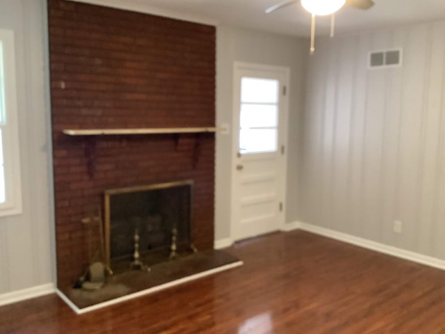 unfurnished living room featuring dark hardwood / wood-style floors, ceiling fan, and a brick fireplace