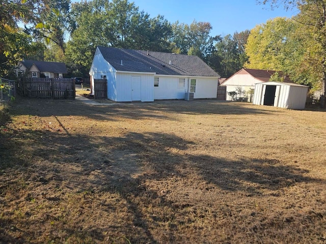 rear view of house featuring a yard, a storage unit, and central air condition unit