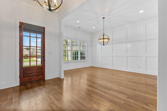 foyer entrance with hardwood / wood-style flooring, ornamental molding, and an inviting chandelier