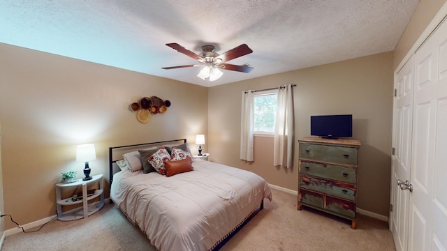 carpeted bedroom with a closet, ceiling fan, and a textured ceiling