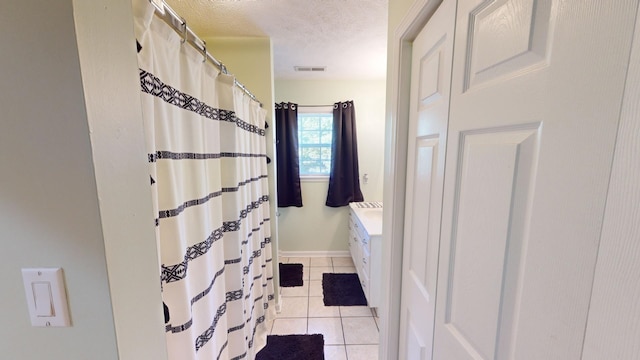 bathroom with vanity, a textured ceiling, and tile patterned flooring