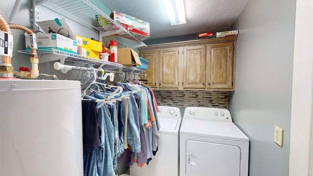 laundry area with cabinets, a textured ceiling, and washing machine and dryer