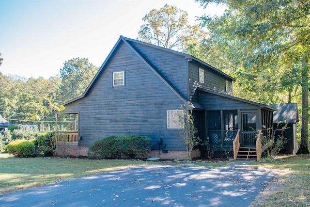 view of home's exterior featuring a sunroom and a lawn