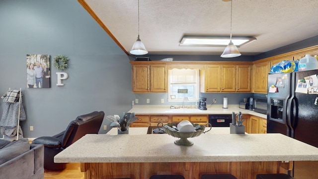 kitchen featuring a textured ceiling, black appliances, hanging light fixtures, and a breakfast bar area