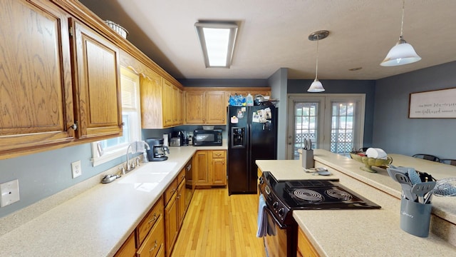 kitchen featuring light hardwood / wood-style floors, black appliances, decorative light fixtures, and plenty of natural light