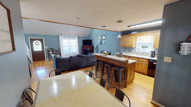 kitchen with dishwasher, light hardwood / wood-style flooring, a kitchen island, and a kitchen breakfast bar