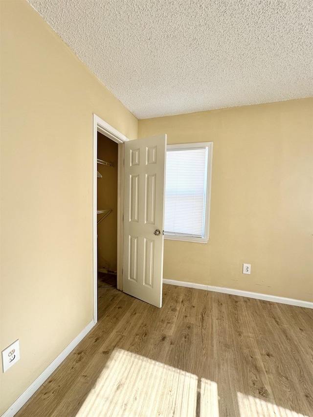 unfurnished bedroom with light wood-type flooring, a textured ceiling, and a closet