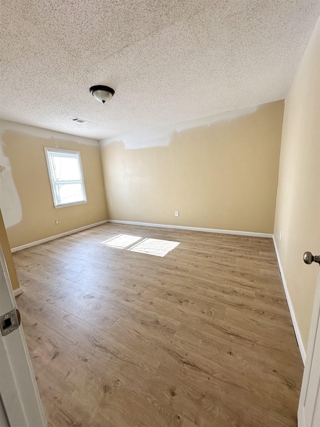 spare room with wood-type flooring and a textured ceiling