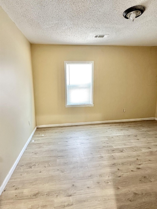 empty room featuring light wood-type flooring and a textured ceiling