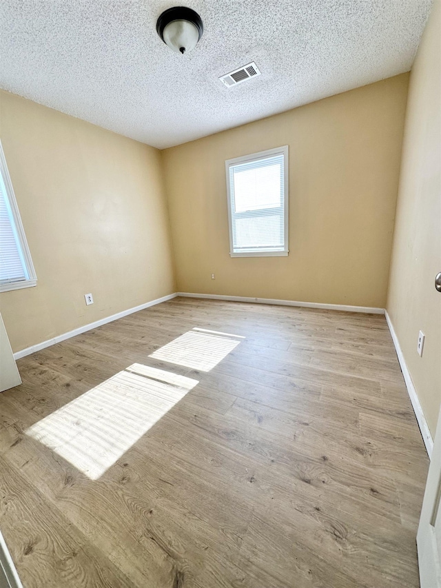 unfurnished room with a textured ceiling and light hardwood / wood-style flooring