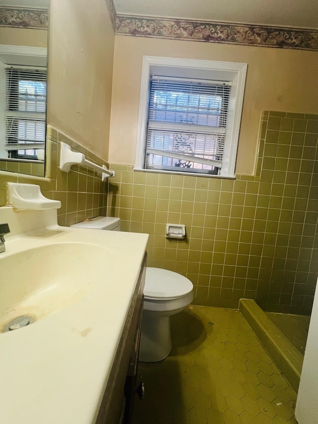 bathroom with tile walls, vanity, toilet, and plenty of natural light