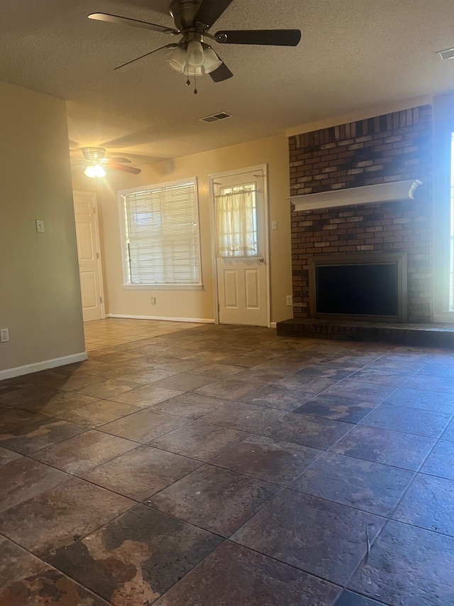 unfurnished living room with a brick fireplace, a textured ceiling, and ceiling fan