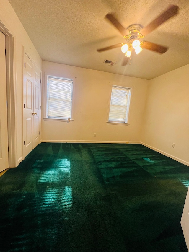 spare room featuring carpet floors, a textured ceiling, and ceiling fan