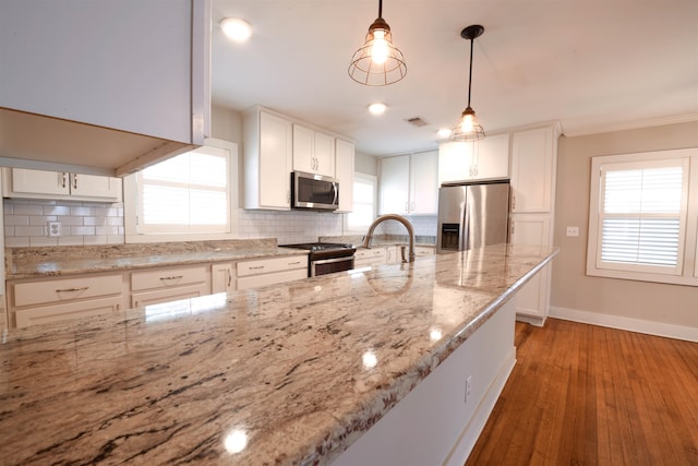 4543 Charleswood Ave, Memphis, TN 38117 - kitchen with decorative backsplash, stainless steel appliances, pendant lighting, white cabinetry, and light hardwood / wood-style floors