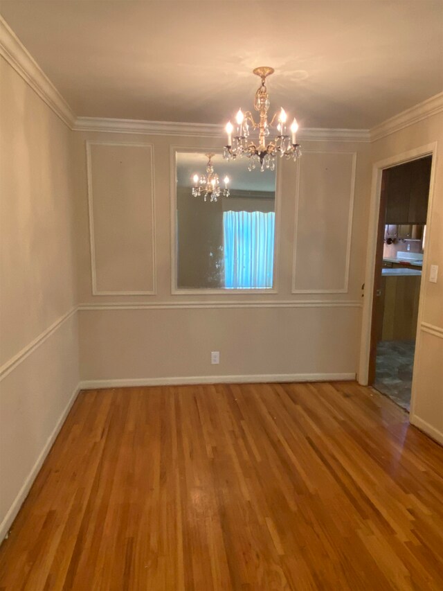 unfurnished dining area featuring ornamental molding, a notable chandelier, and hardwood / wood-style floors